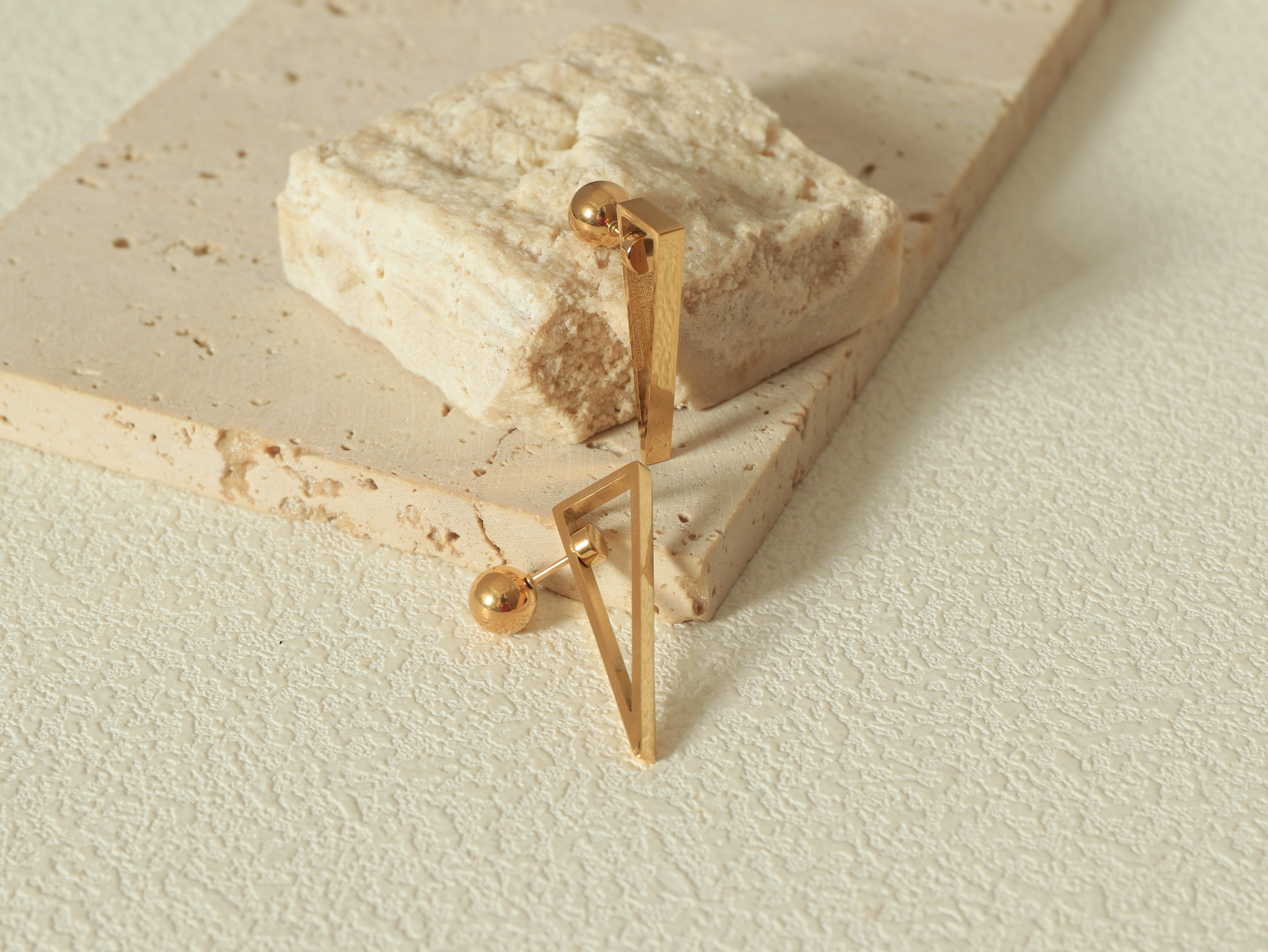 Close-up of the Equinox Earring showcasing the Revolve Closure mechanism and scratch-resistant 14k gold surface - Flat Lay - Angled View 1