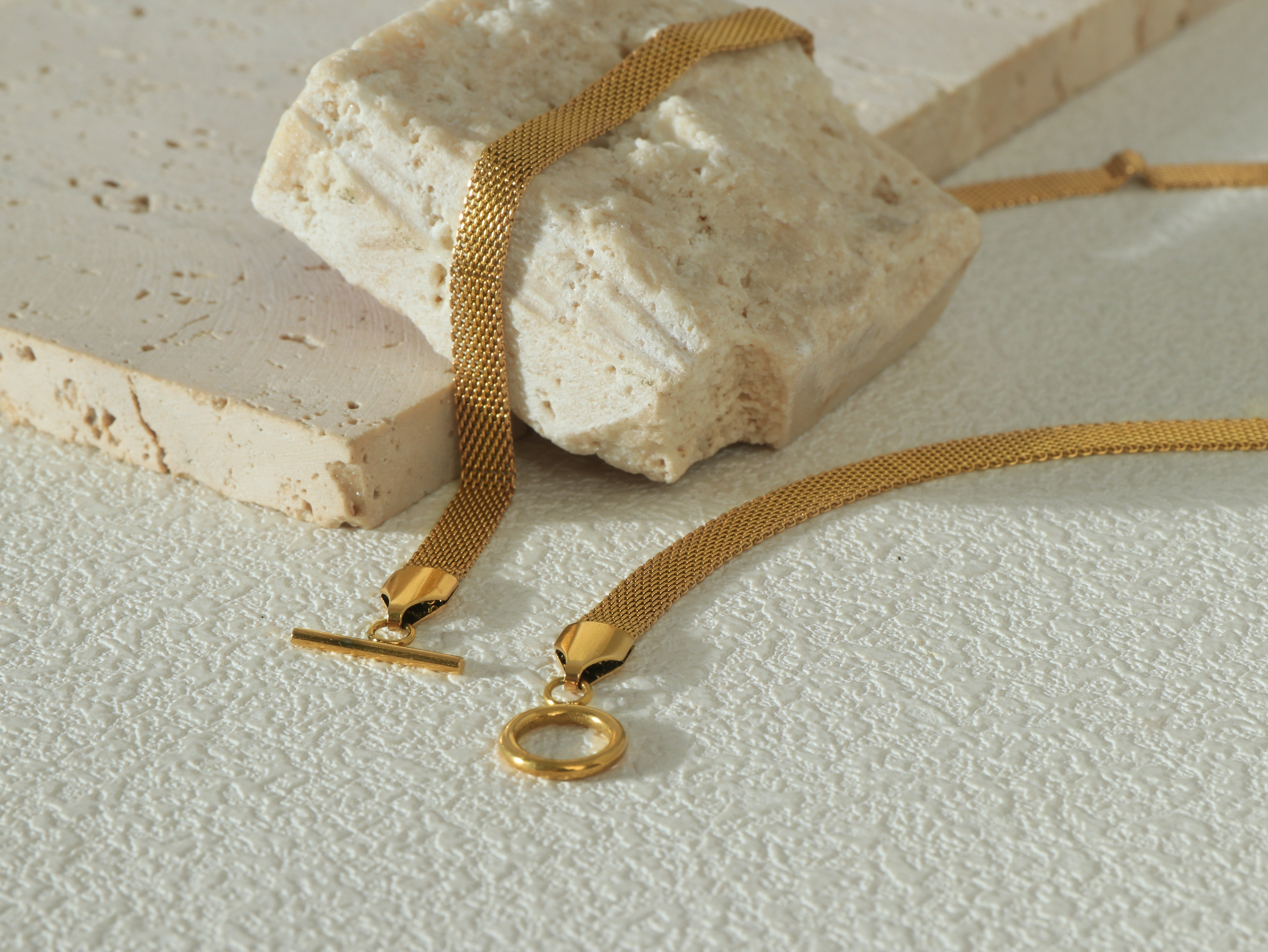 Close up flat lay shot of the Dominion Necklace OT clasp, showcasing its unique, modern design and gold-plated stainless steel construction.
