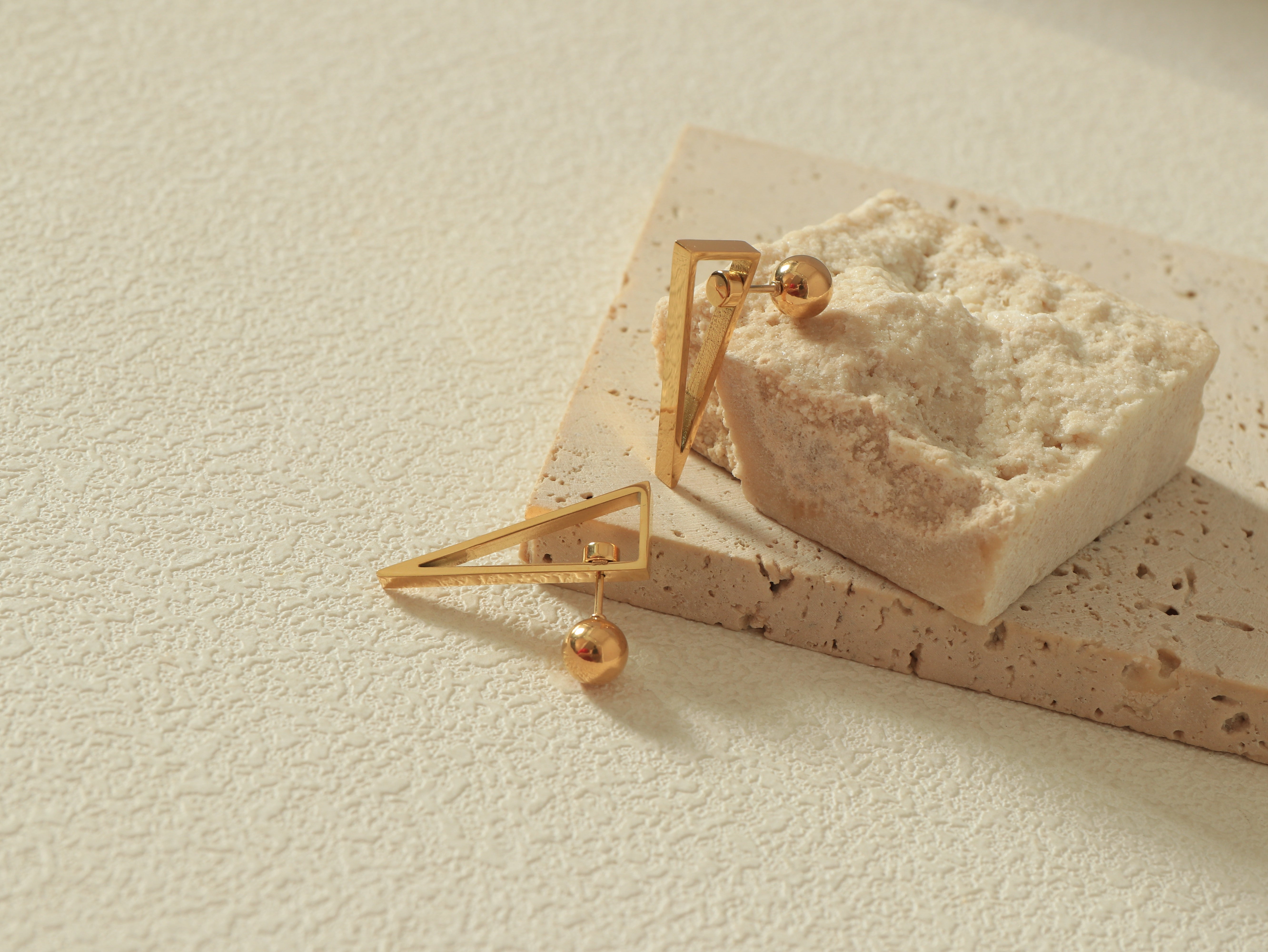 Close-up of the Equinox Earring showcasing the Revolve Closure mechanism and scratch-resistant 14k gold surface - Flat Lay - Angled View 2