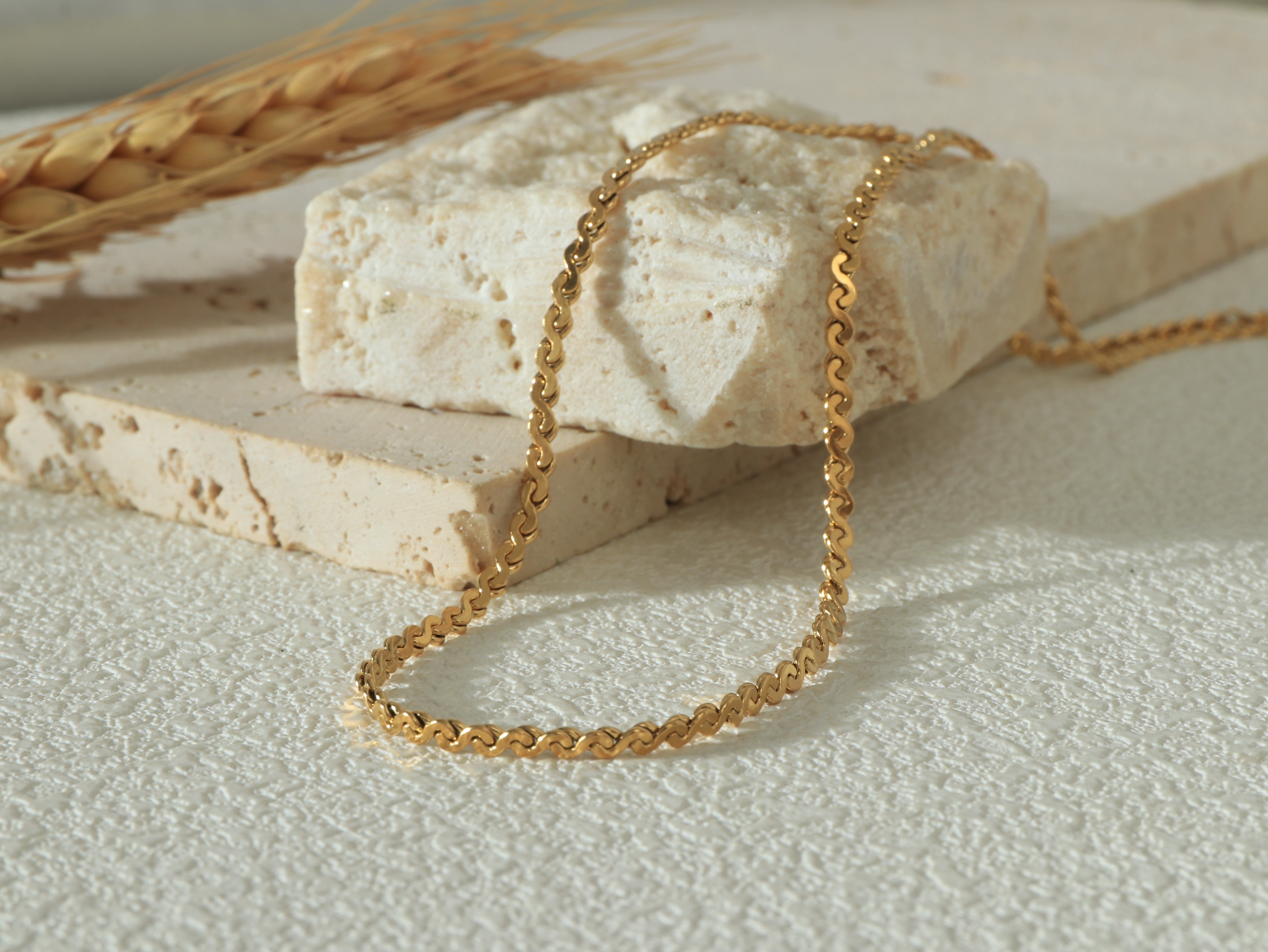 Allure Gold Chain styled in a gentle curve flat lay, highlighting its polished 18k gold finish and minimal yet bold aesthetic - Image 1