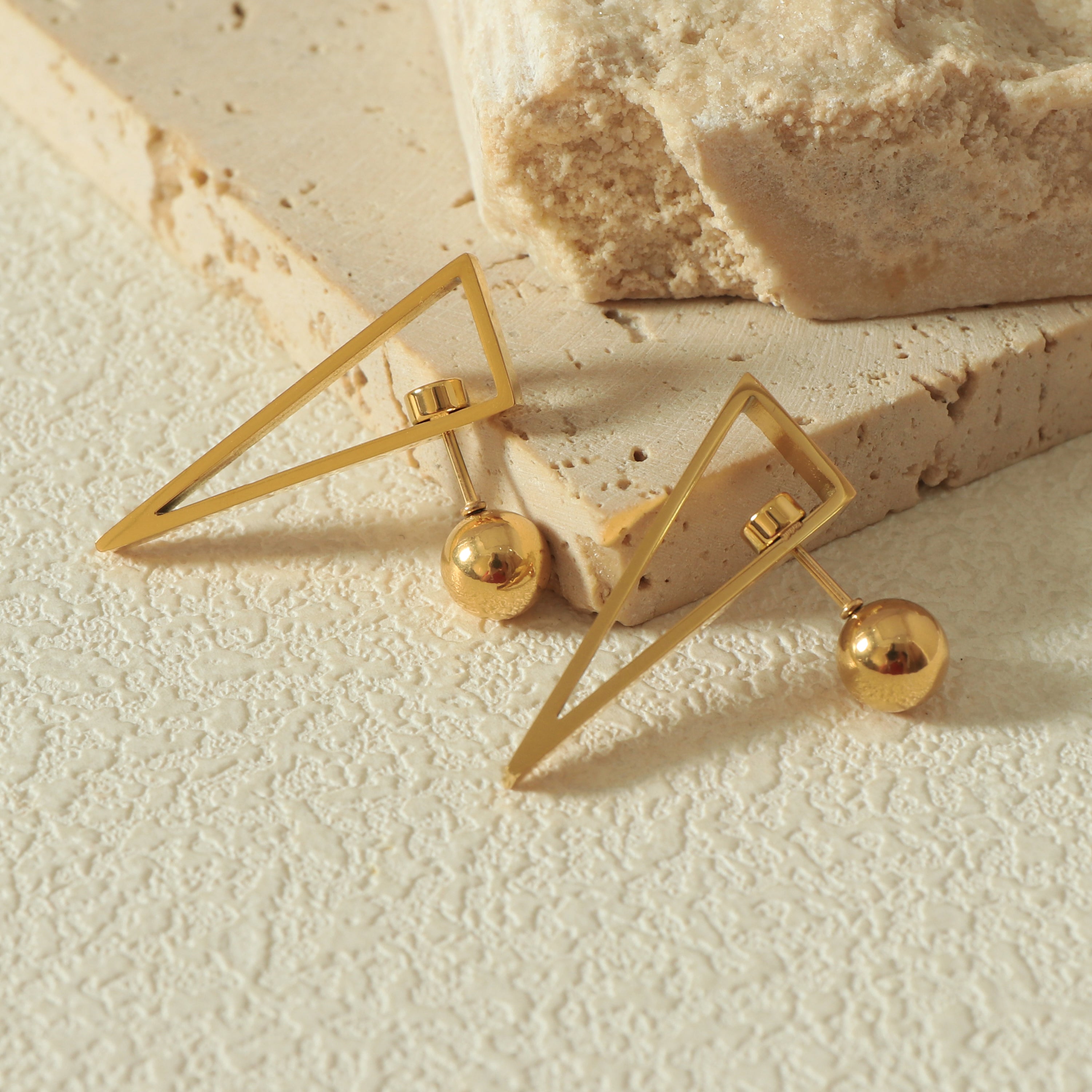 Close-up of the Equinox Earring showcasing the Revolve Closure mechanism and scratch-resistant 14k gold surface - Styled Flat Lay 1