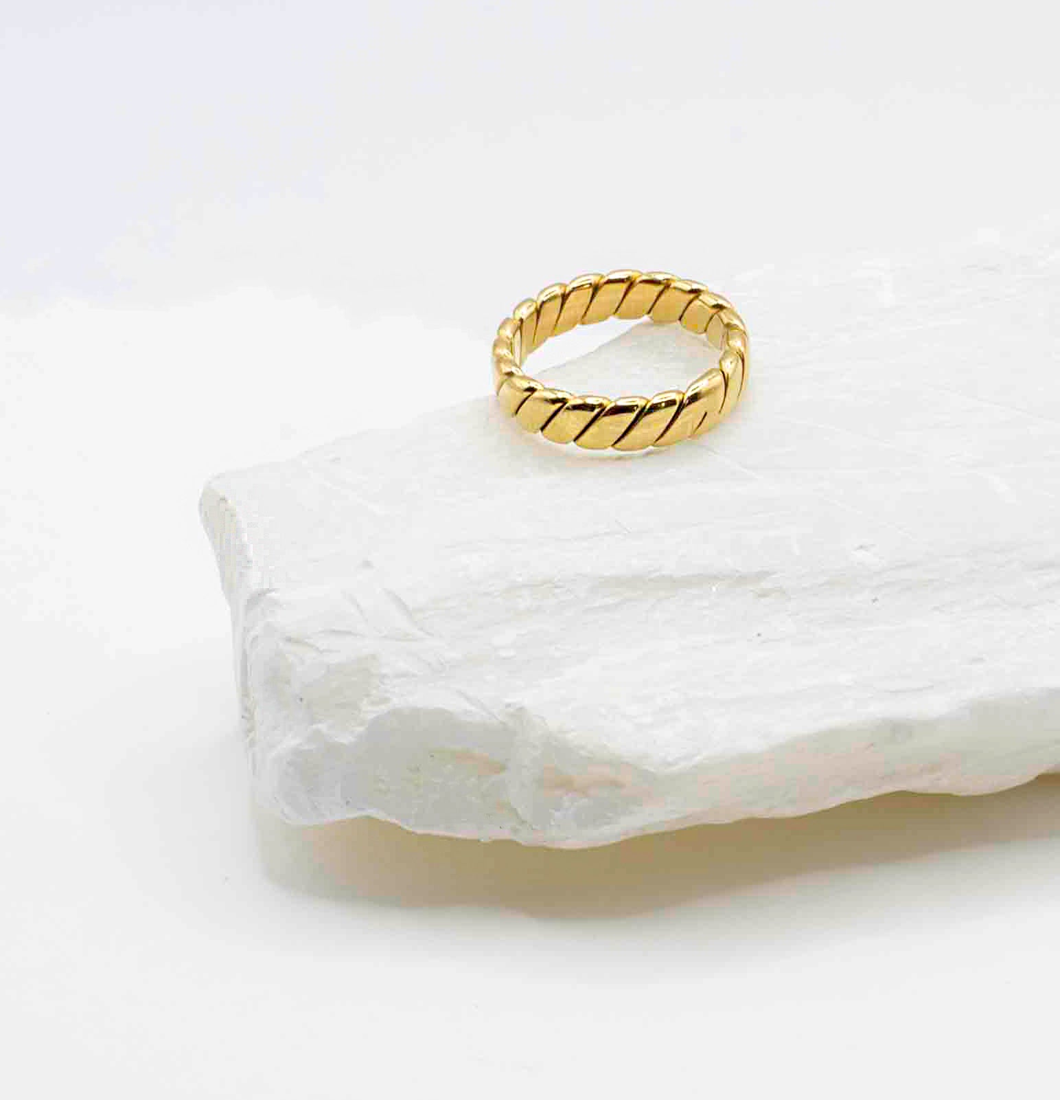 Flat lay of the Venus Gold Ring showcasing its elegant braided detail and lustrous 18k gold shine