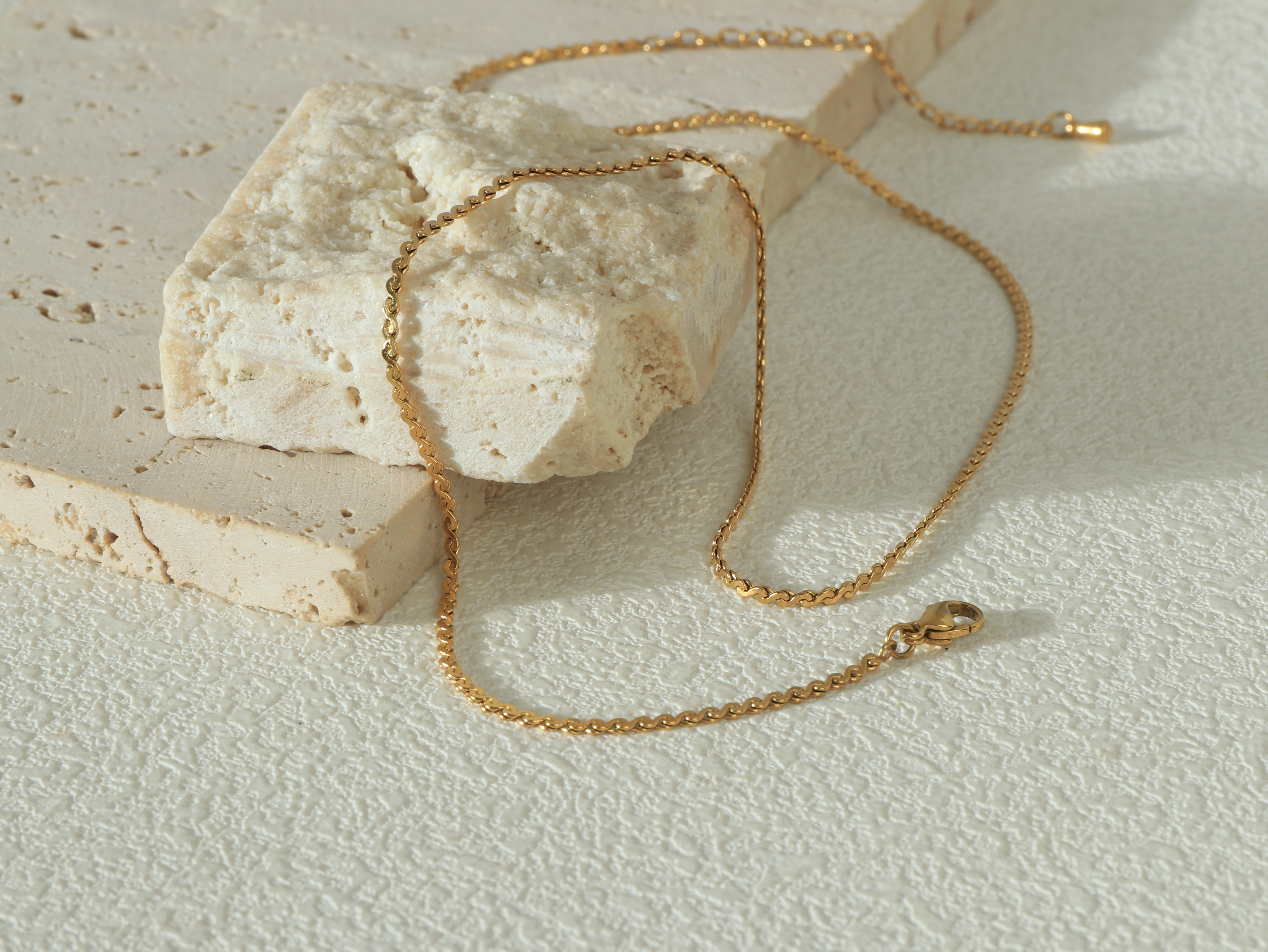 Allure Gold Chain arranged in a curved shape, showing its minimal, delicate design and waterproof gold coating - Image 1