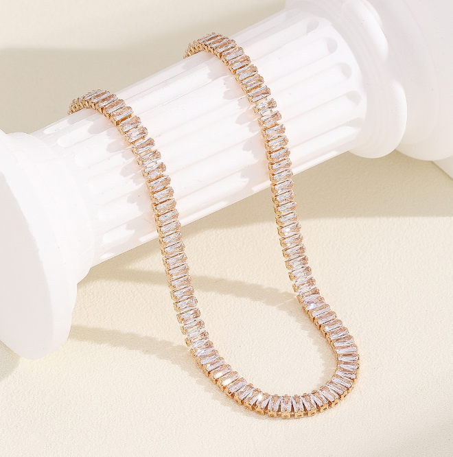 Lustre Gold Necklace draped over a jewelry holder, showcasing its crystal details and 18k gold shine.