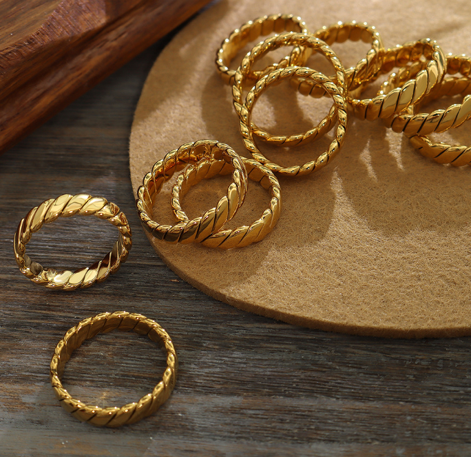 Multiple Venus Gold Rings on a jewelry holder emphasizing its unique braided texture and rich 18k gold tone