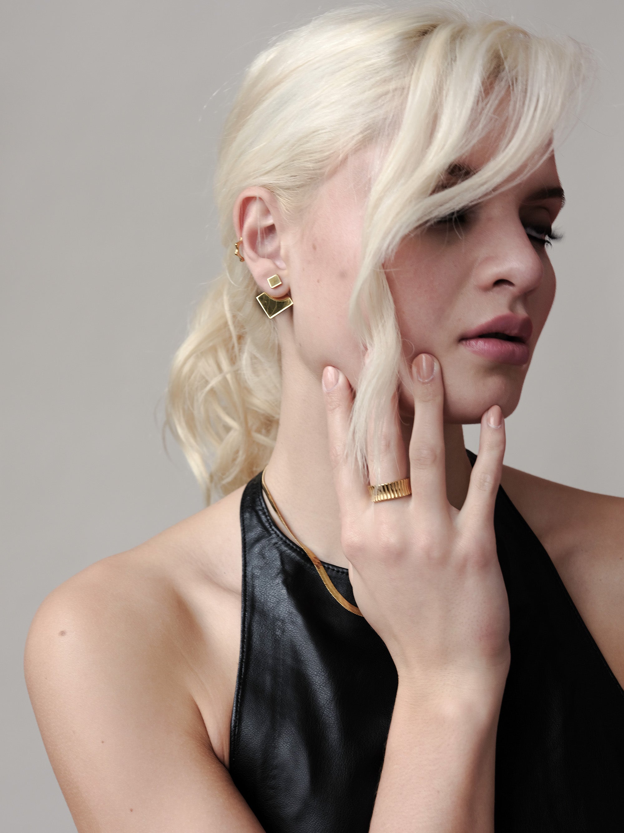 Close-up of the Revolve Rhomb Earrings worn by a model, showcasing the polished 18k gold finish, stainless steel base.