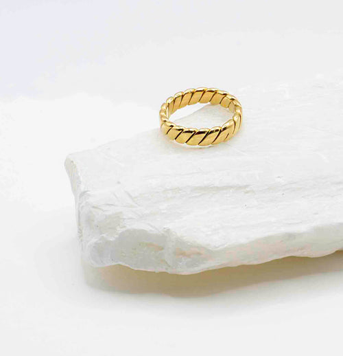  Flat lay of the Venus Gold Ring showcasing its elegant braided detail and lustrous 18k gold shine