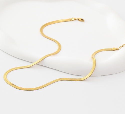 Flat lay 1 of the Cleo Gold Necklace arranged neatly, highlighting its polished 14k gold surface and closure design.