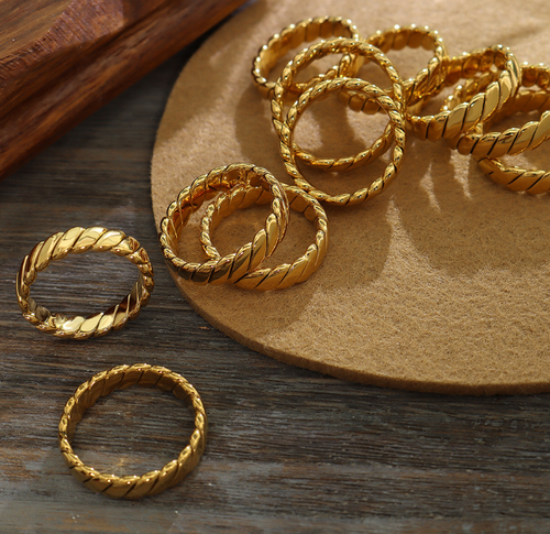 Multiple Venus Gold Rings on a jewelry holder emphasizing its unique braided texture and rich 18k gold tone 