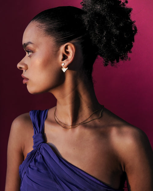 Model wearing the bold Revolve Rhomb Earrings 18k gold earrings, showing the structured front-back design and signature Revolve Closure.