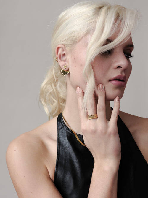 Close-up of the Revolve Rhomb Earrings worn by a model, showcasing the polished 18k gold finish, stainless steel base.